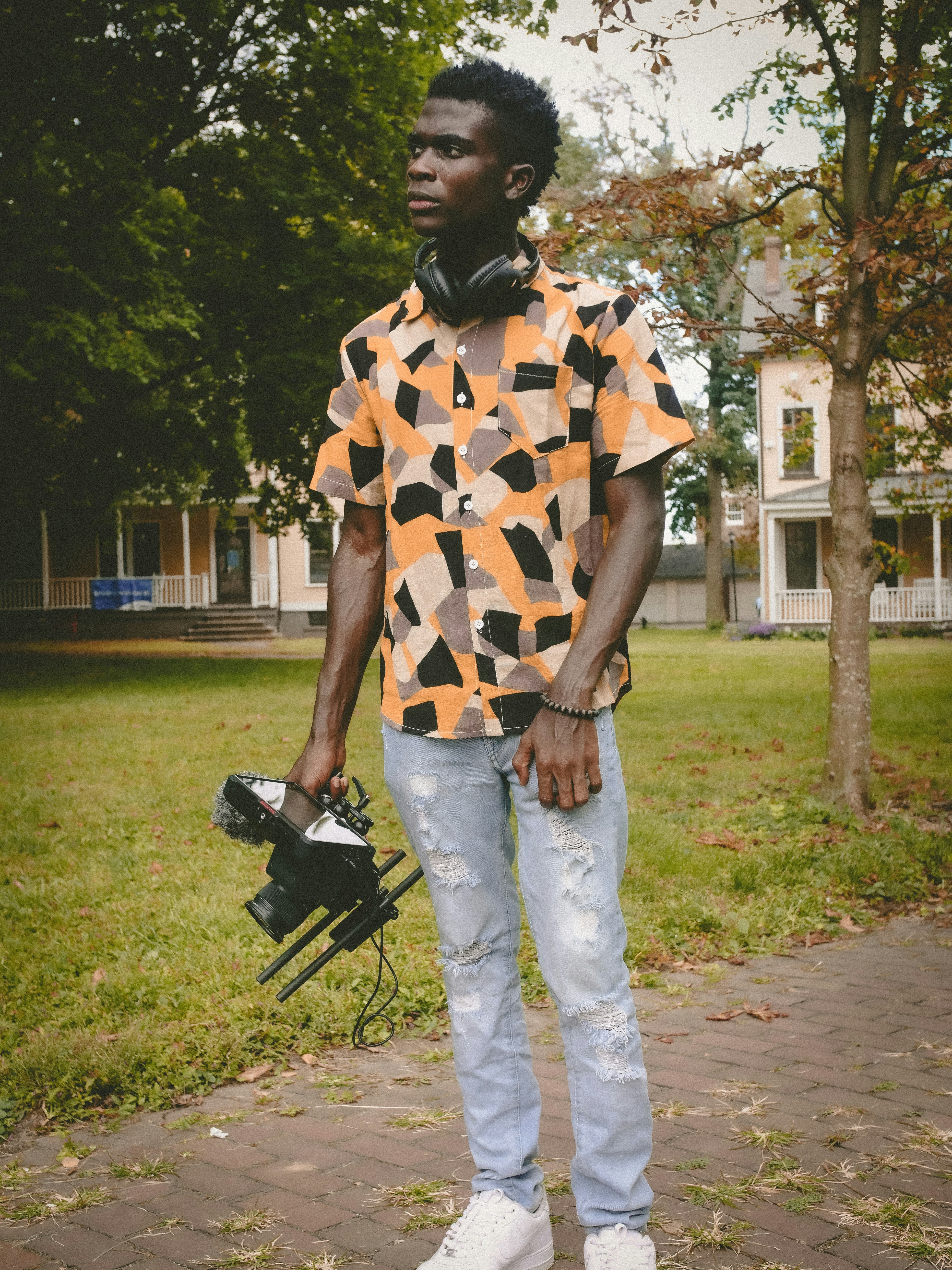 man in white and brown checkered button up shirt and white pants standing on green grass